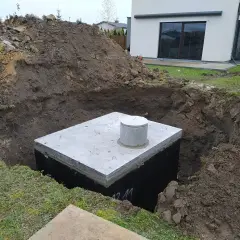 Zbiornik na deszczówkę w wykopie, gotowy do podłączenia do rynny.