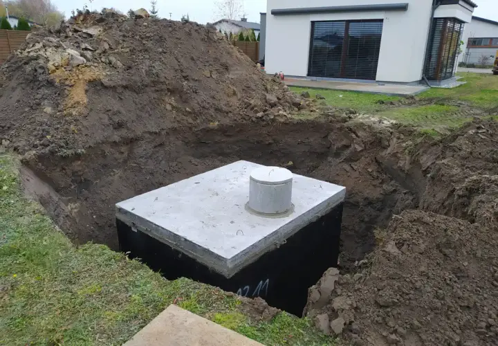 Zbiornik na deszczówkę w wykopie, gotowy do podłączenia do rynny.